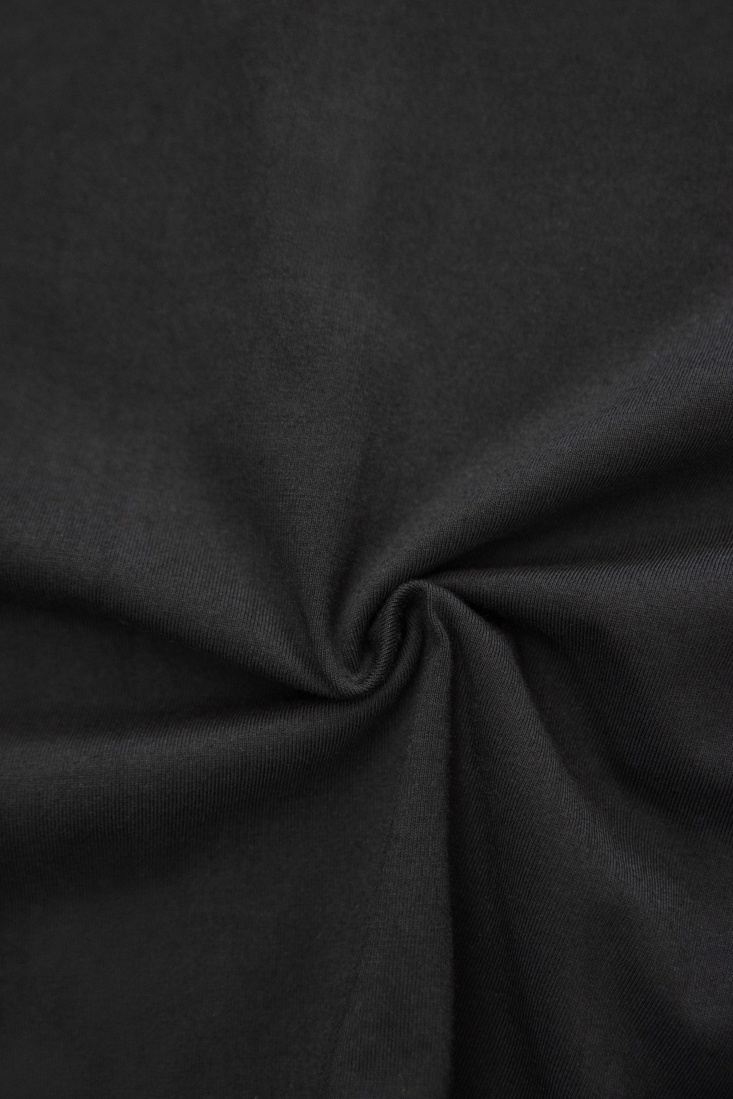 Zoomed-in fabric texture of black cotton t-shirt. Highlights soft, breathable material used in premium unisex short sleeve design.