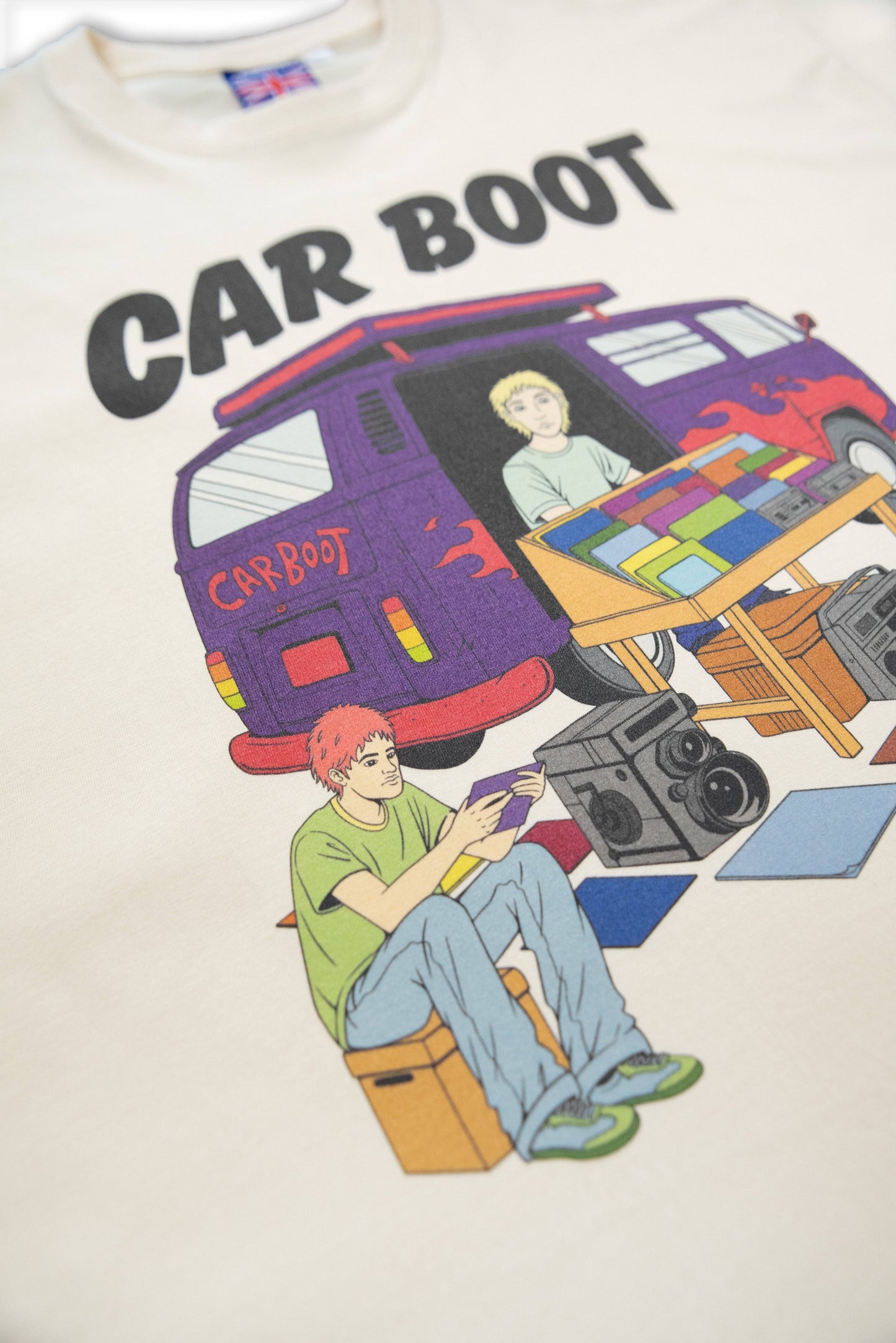 Detailed view of Cream T-Shirt - Car Boot Print with vibrant illustration of car boot market, highlighting colorful characters and vintage items.