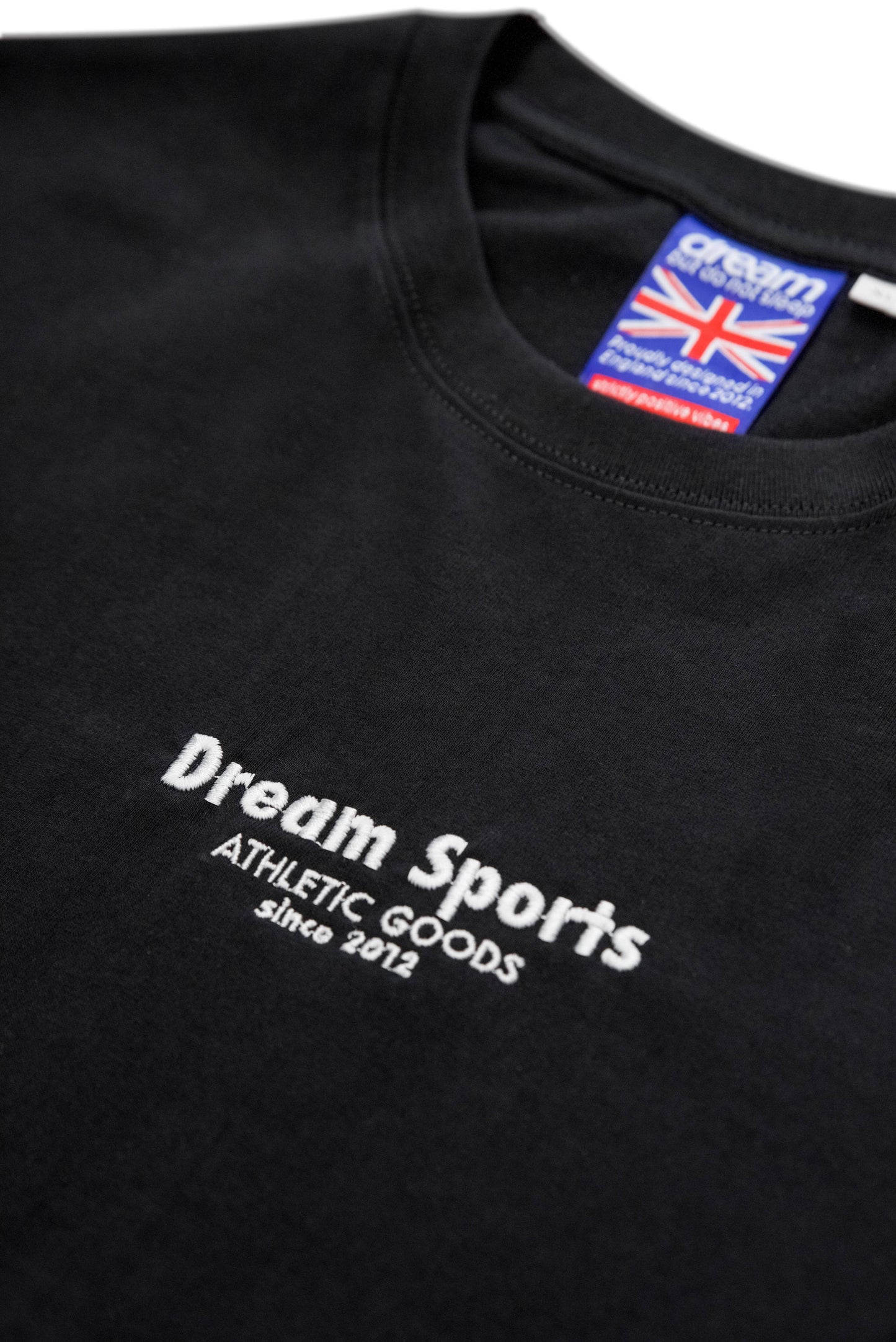 Detailed view of embroidered Dream Sports logo on black cotton t-shirt. Features UK tag and premium stitching for quality assurance.
