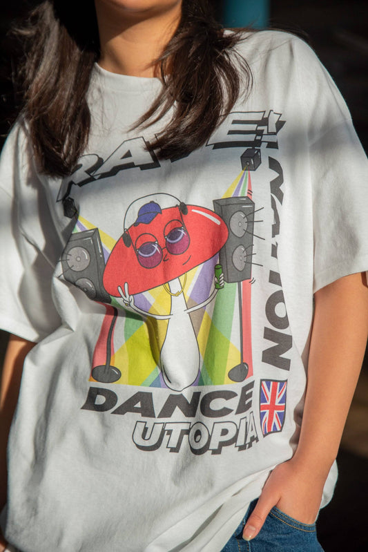Close-up of white unisex t-shirt featuring colorful mushroom dance utopia graphic with speakers and UK flag. Relaxed fit, 100% cotton.