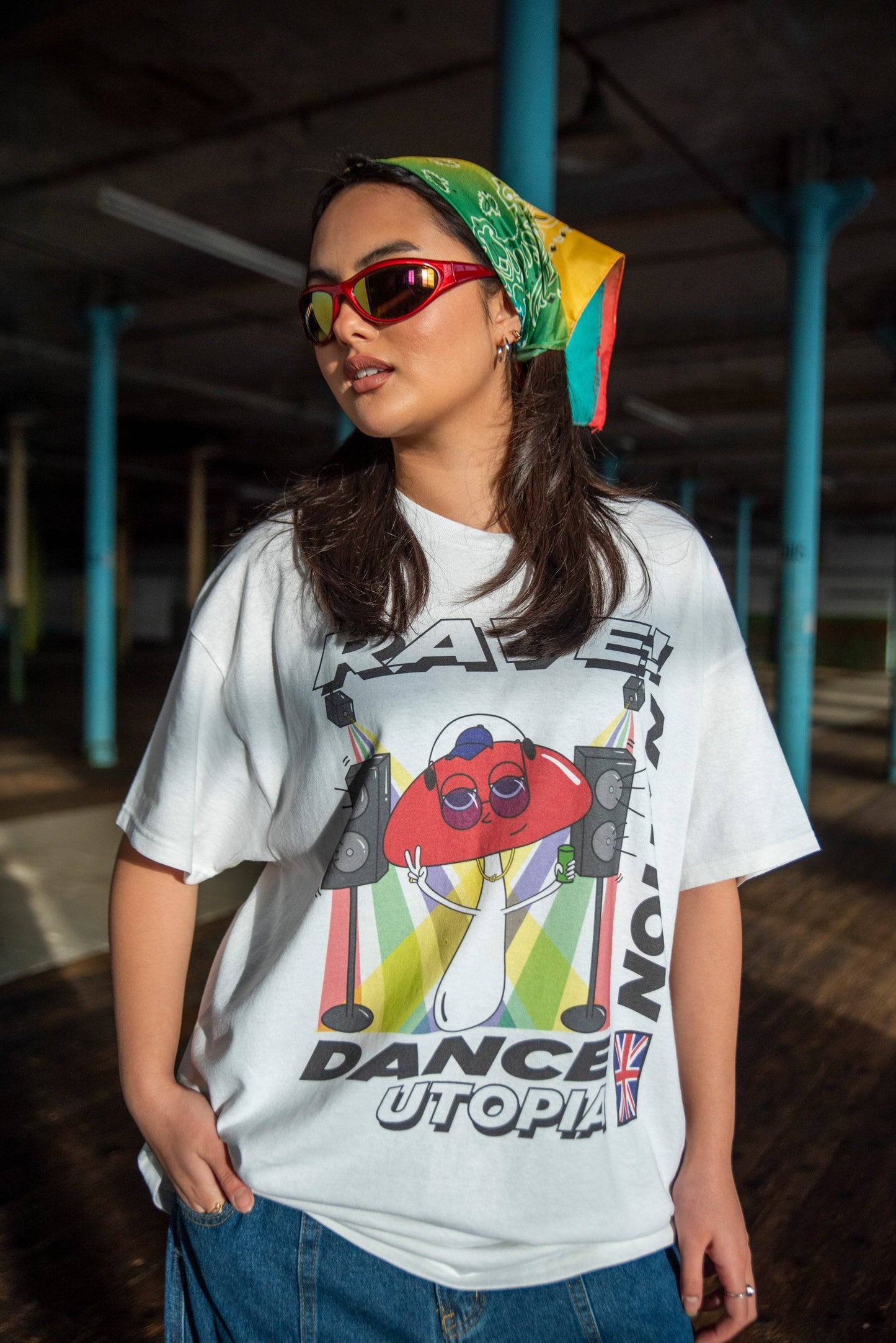 White graphic t-shirt with mushroom dance utopia print worn by model. Unisex relaxed fit cotton tee ideal for casual streetwear style.