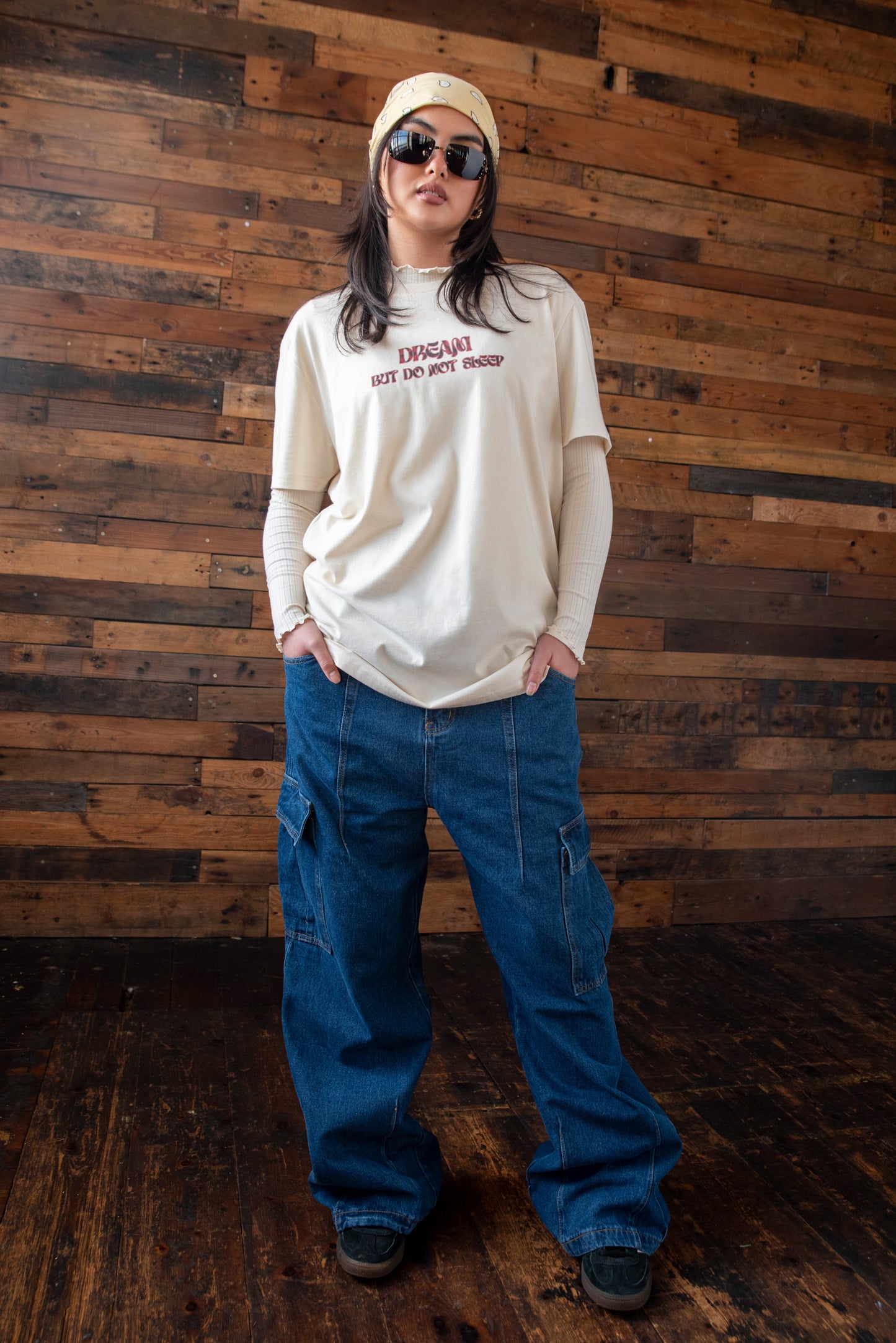 Full-body view of relaxed fit natural cotton t-shirt with logo print, paired with wide-leg jeans and layered long sleeves.