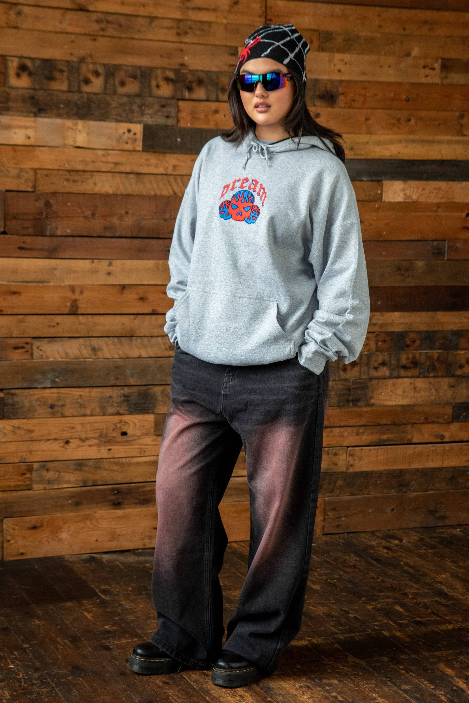 Unisex Heather Grey Skull Hoodie with bold flaming embroidery, styled with ombre black jeans and streetwear accessories for a Y2K-inspired look.