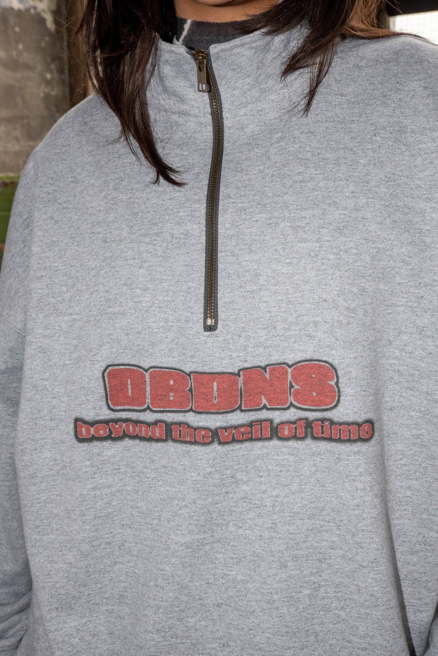 Close-up of DBDNS 'Beyond The Veil Of Time' print on heather gray 1/4 zip sweatshirt, showcasing bold graphic detail on cotton fabric.