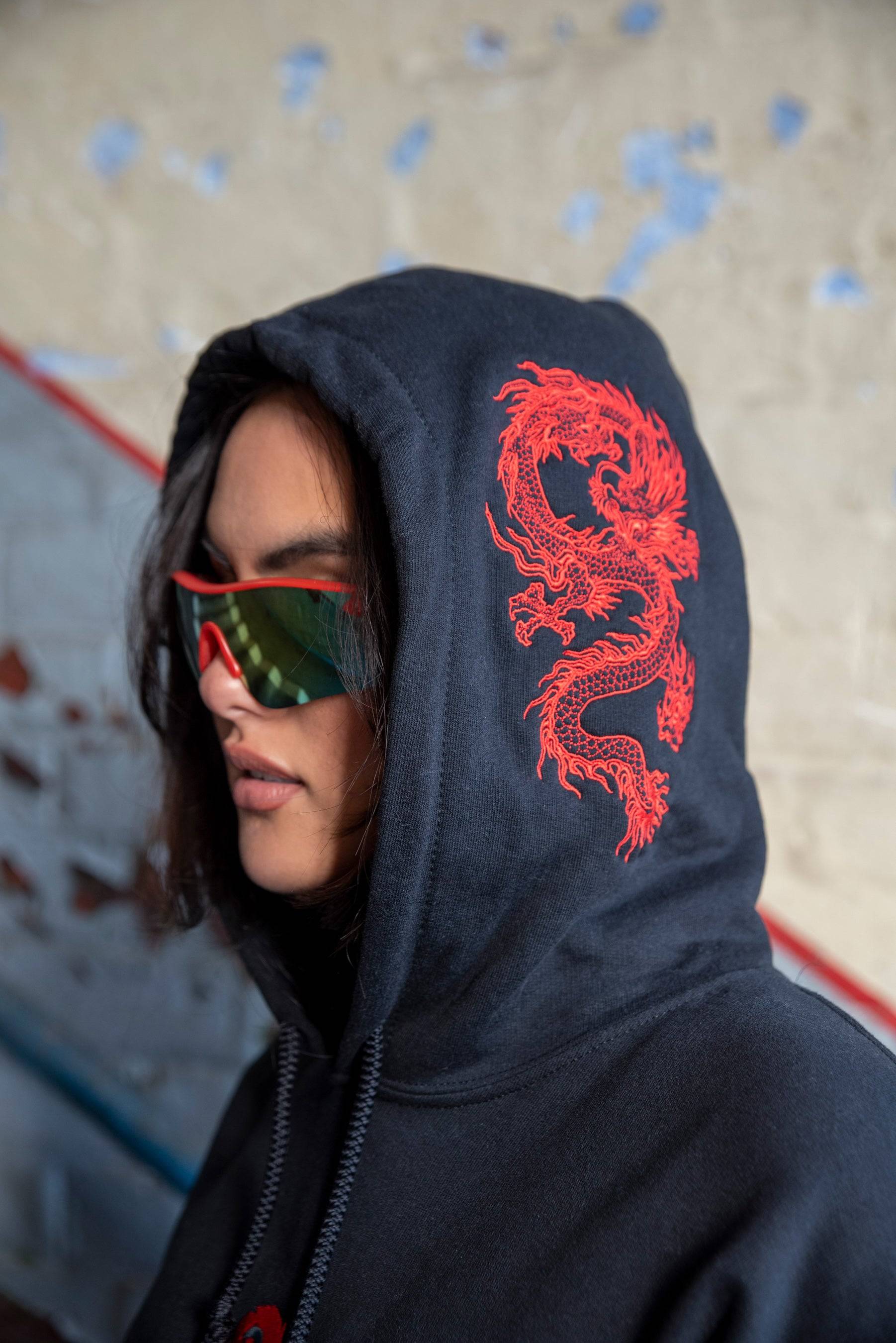 Profile shot of model wearing black hoodie with red dragon embroidery on hood, part of the Y2K-inspired streetwear collection.