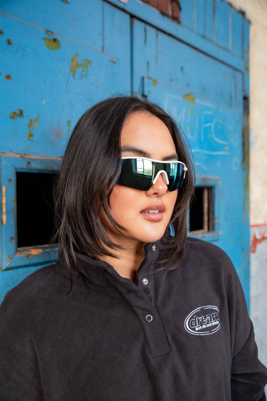 Close-up of model wearing Black Cropped Fleece Sweatshirt with Oval Logo. Features snap-button collar and soft heavyweight fabric.