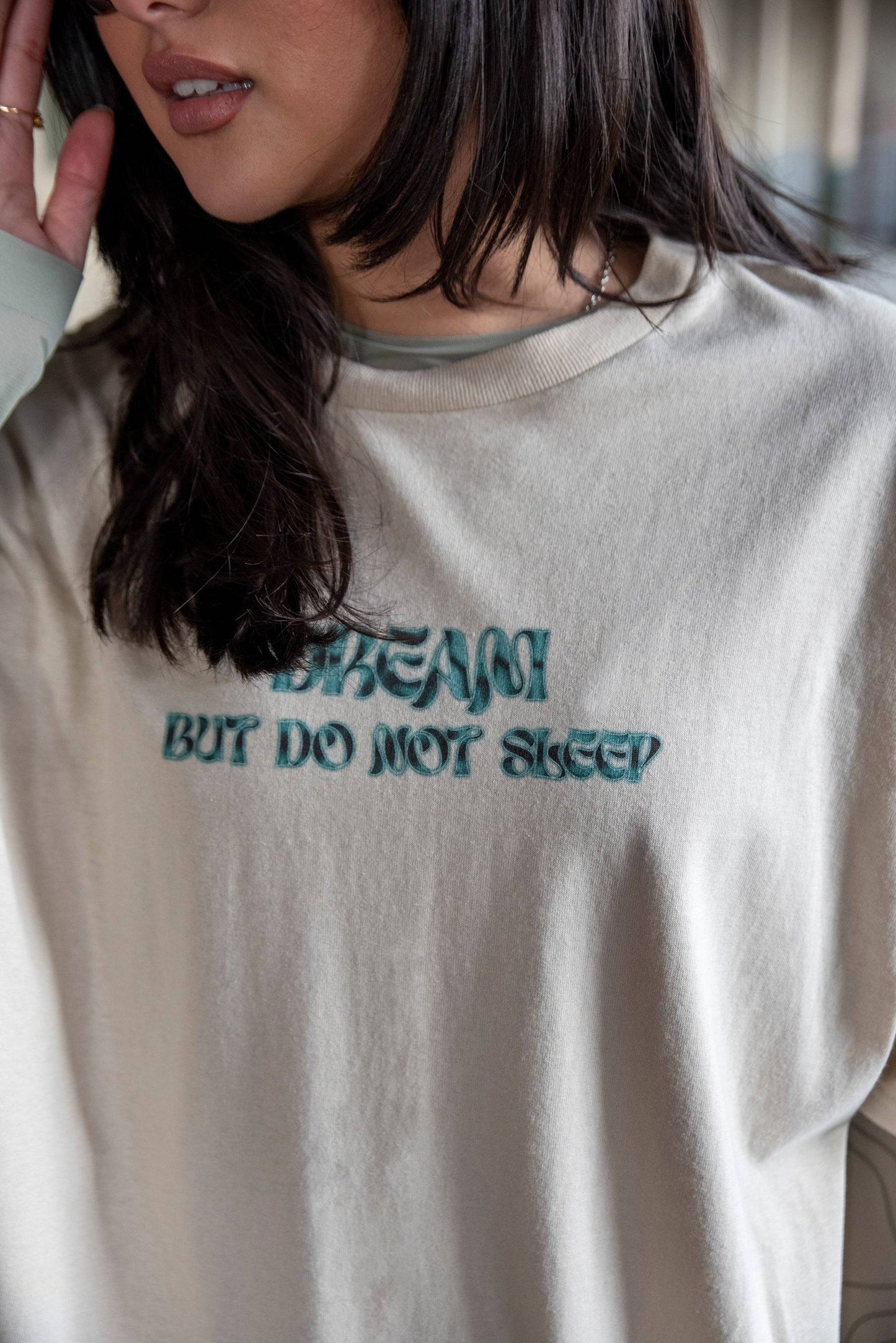 Close-up of Short Sleeved T-Shirt in Sand - Unisex Cotton Tee showing 'DREAM BUT DO NOT SLEEP' cursive logo print on soft 100% cotton fabric.