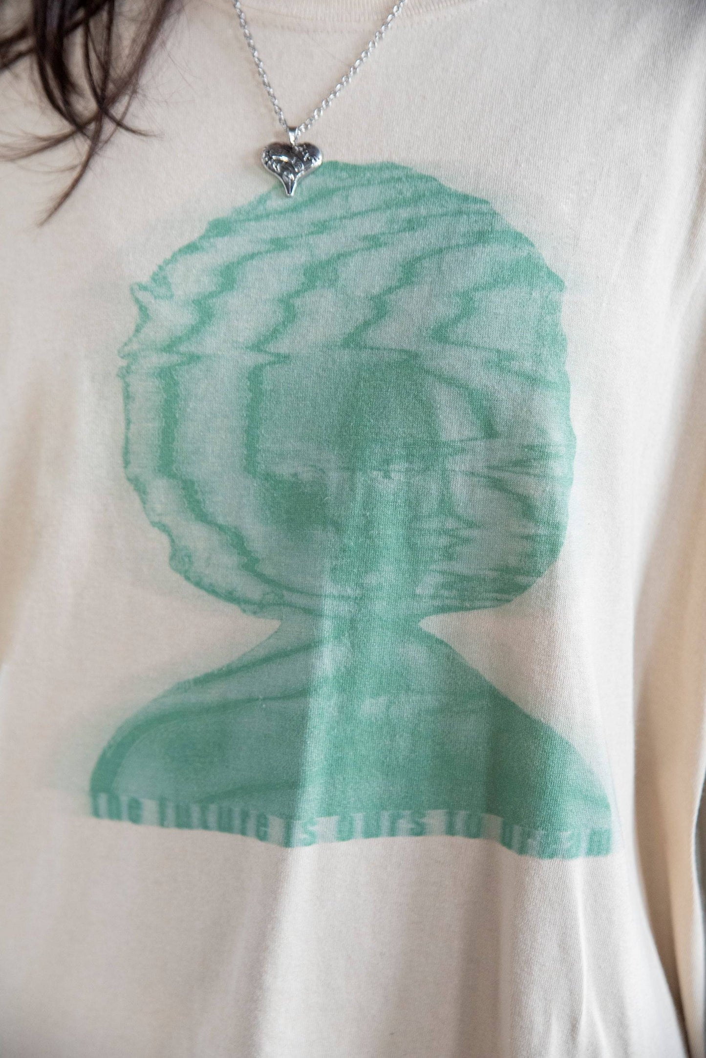 Close-up of green abstract face graphic and 'The Future Is Ours To Dream' text on soft cotton Short Sleeved T-Shirt - Unisex Graphic Tee.