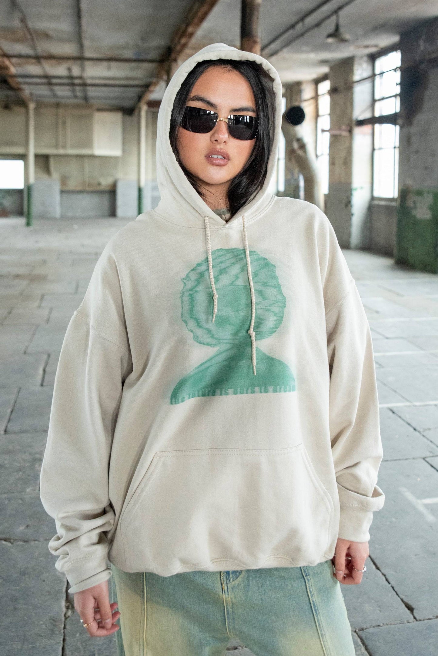 Unisex sand hoodie with green 'The Future Is Ours To Dream' print, relaxed fit cotton streetwear styled in urban setting.