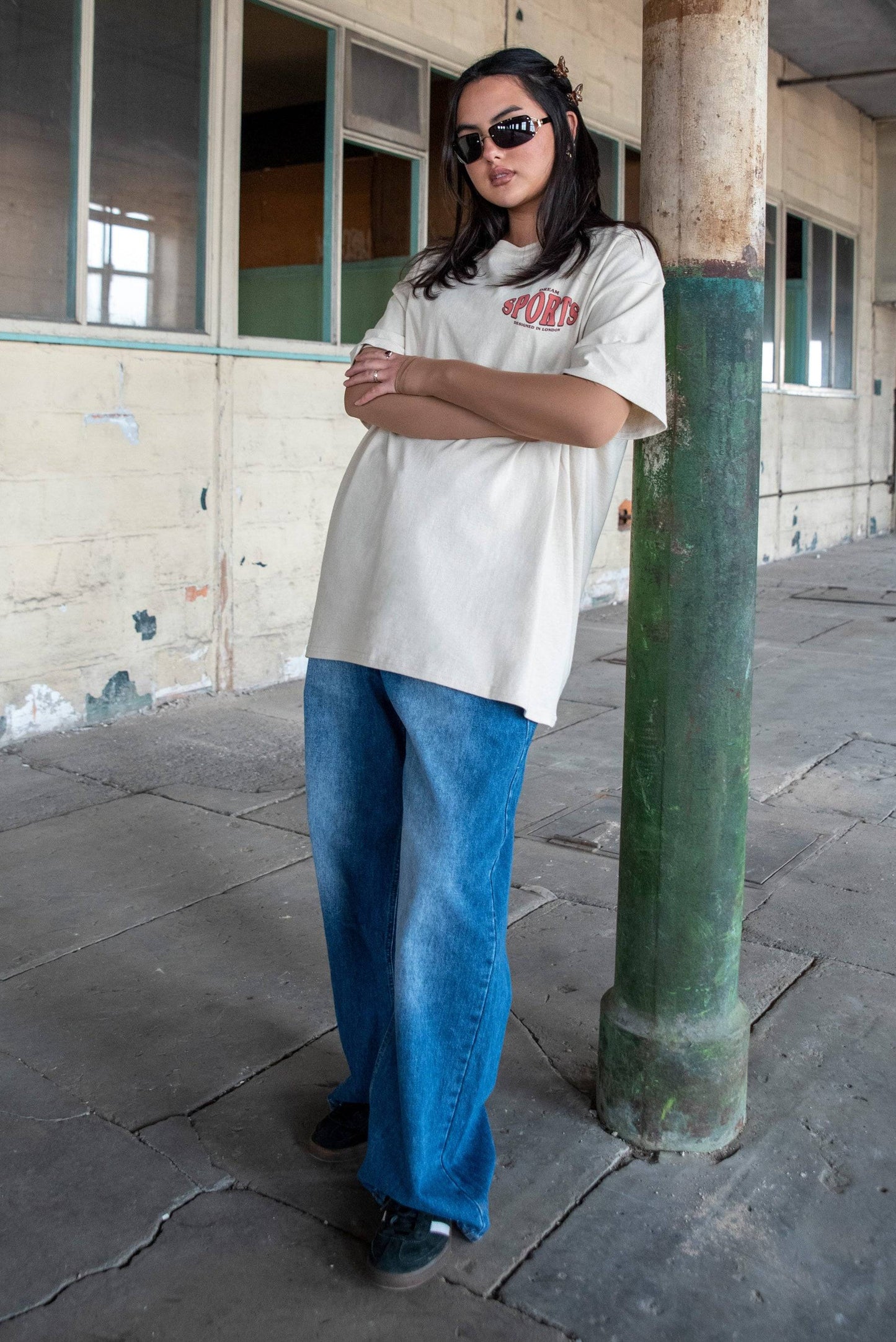 Model wearing Dream Sports T-Shirt - Designed in London paired with wide-leg jeans. Soft cotton tee with urban casual appeal.