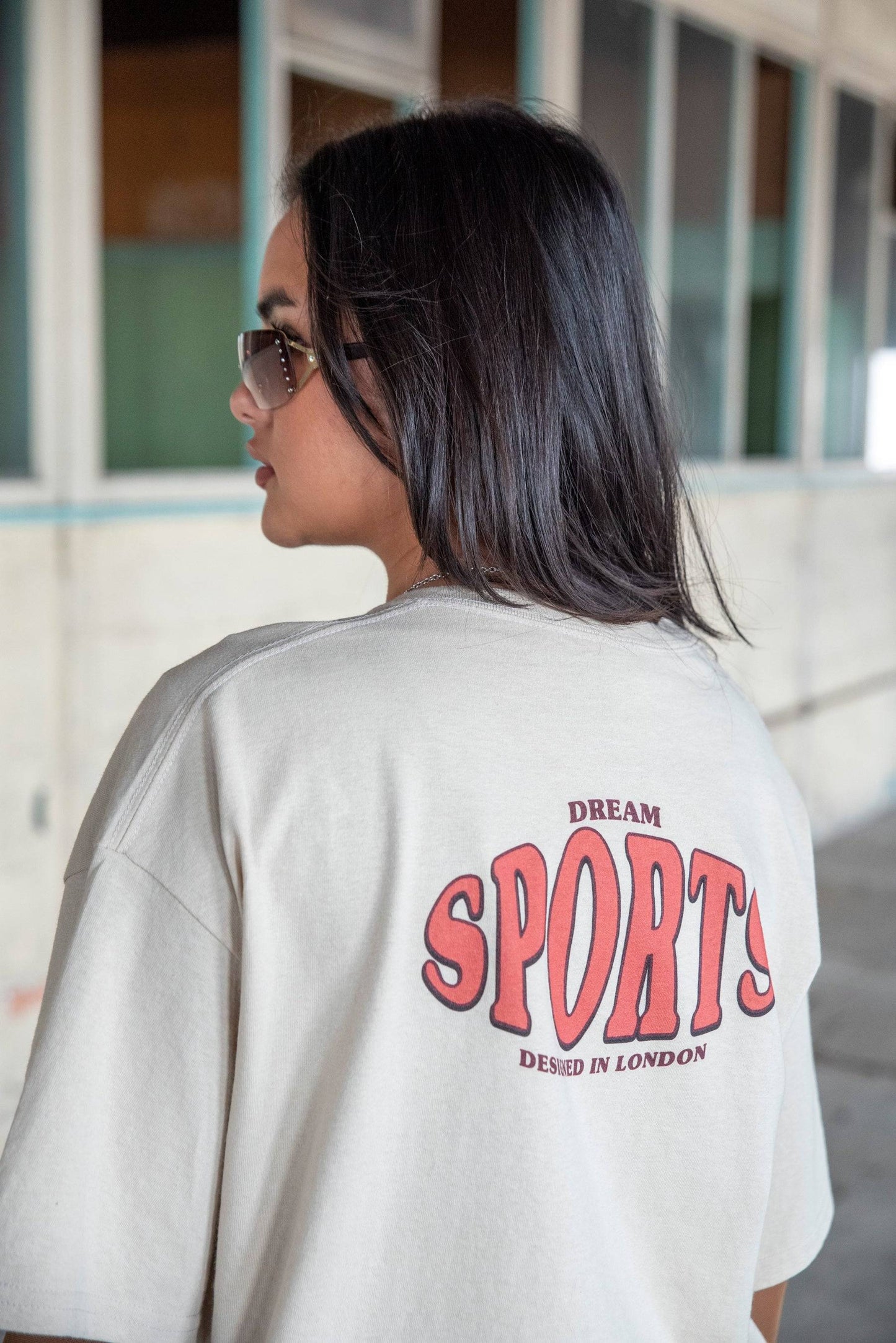 Back view of Dream Sports T-Shirt - Designed in London showing bold red print on sand cotton fabric. Relaxed fit streetwear style.