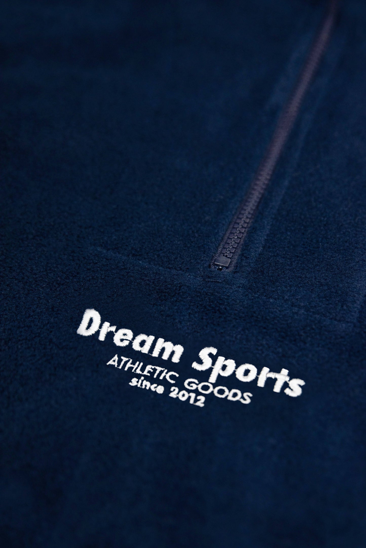 Detailed view of Dream Sports tonal embroidery and zipper on heavyweight navy fleece, unisex relaxed fit sweatshirt.