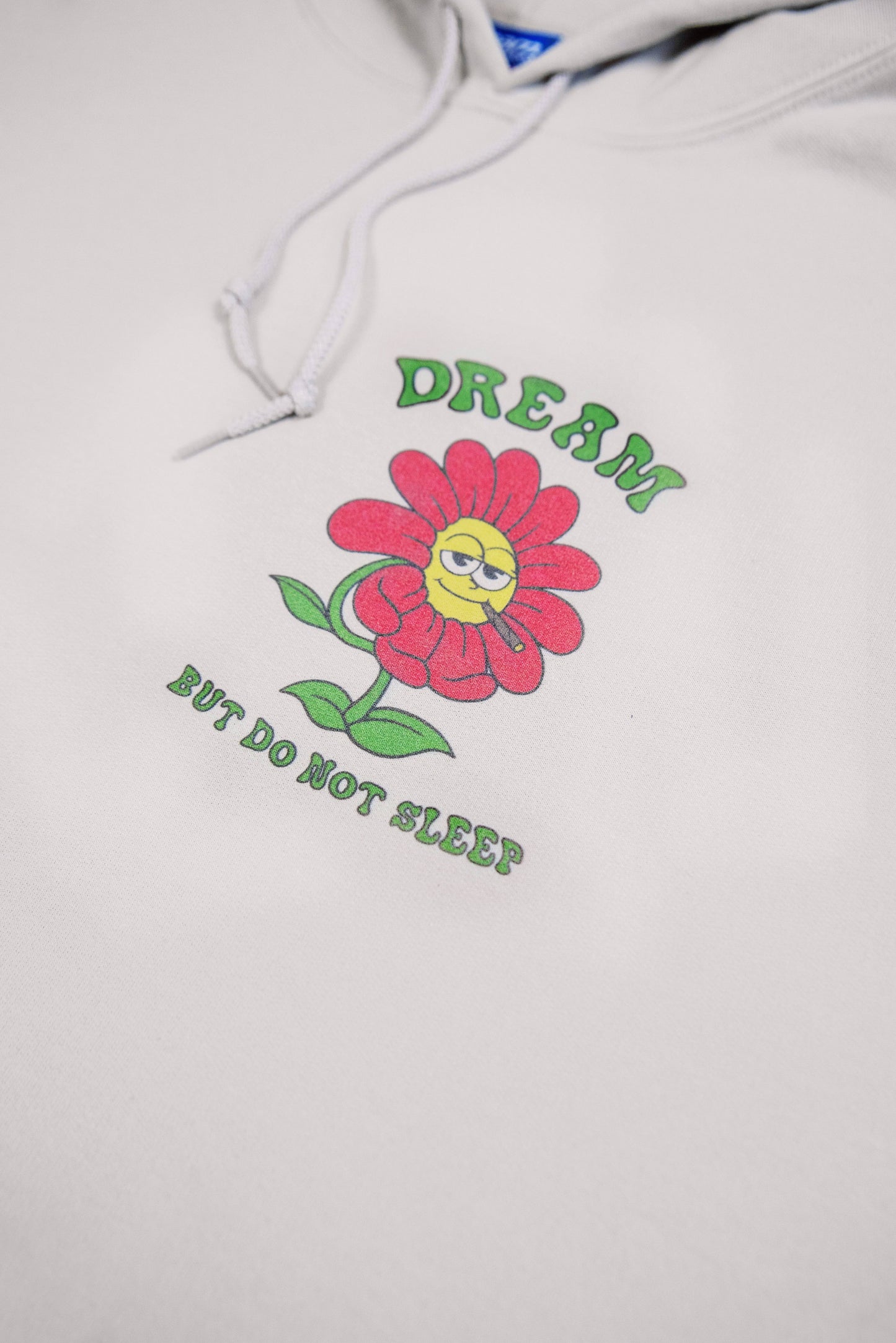 Macro shot of front flower print on sand hoodie with motivational slogan. Vibrant Y2K graphic on soft heavyweight cotton fabric.