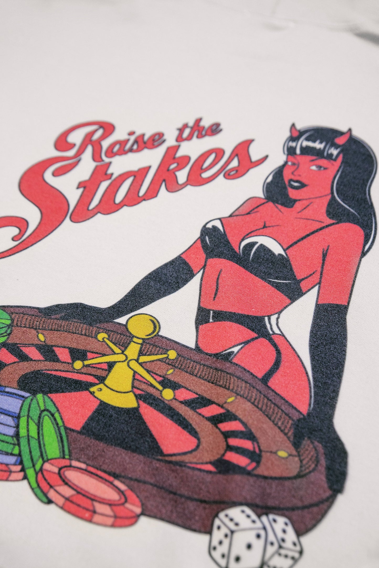 Detailed view of roulette print on unisex sand hoodie with vibrant casino elements and retro-style devil pin-up illustration.