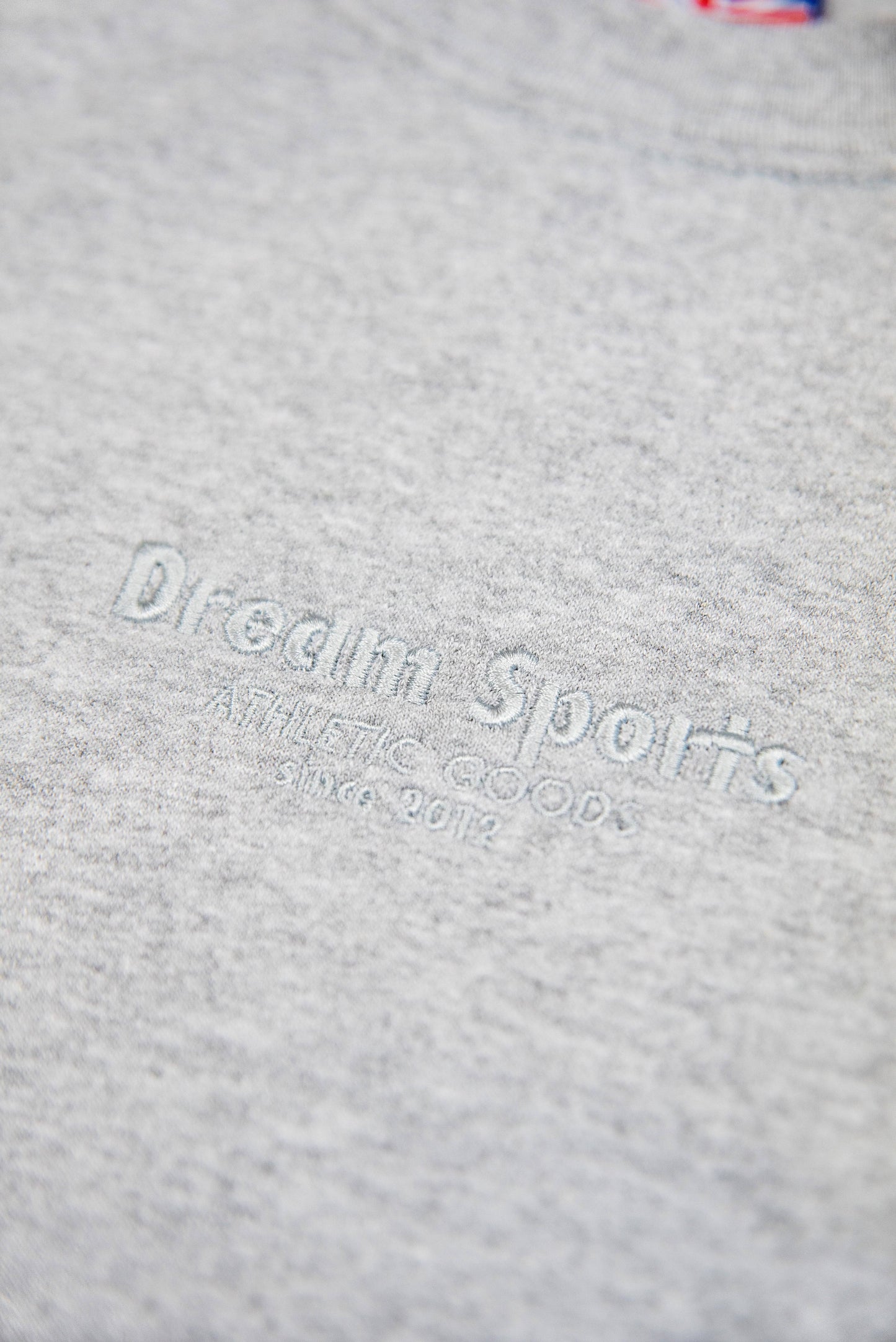 Detailed embroidery reading 'Dream Sports Athletic Goods Since 2012' on Heather Grey Sweatshirt, emphasizing premium craftsmanship.