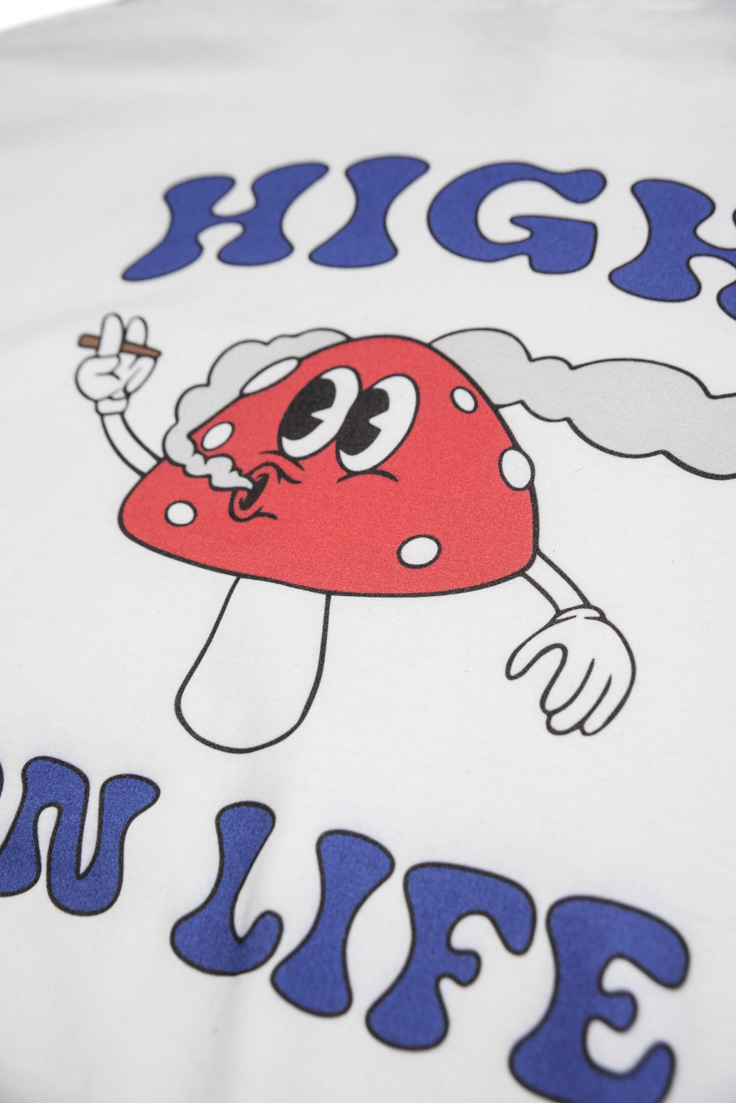 Close-up of mushroom print and 'High On Life' text on white hoodie. Heavyweight cotton fabric with vibrant cartoon-style design.