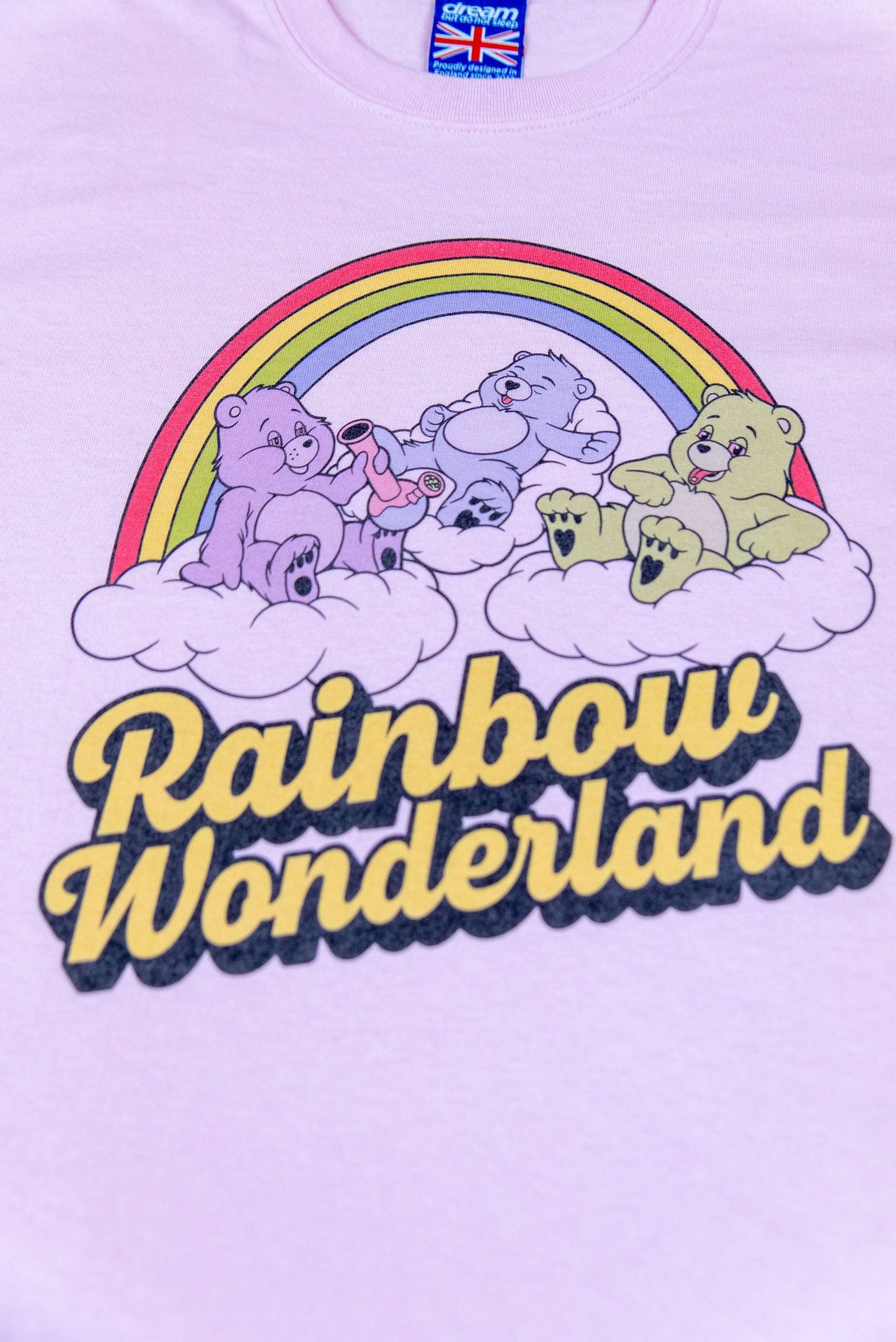 Close-up of light pink cotton t-shirt with vibrant DTG 'Rainbow Wonderland' print showing colorful cartoon bears and rainbow design.