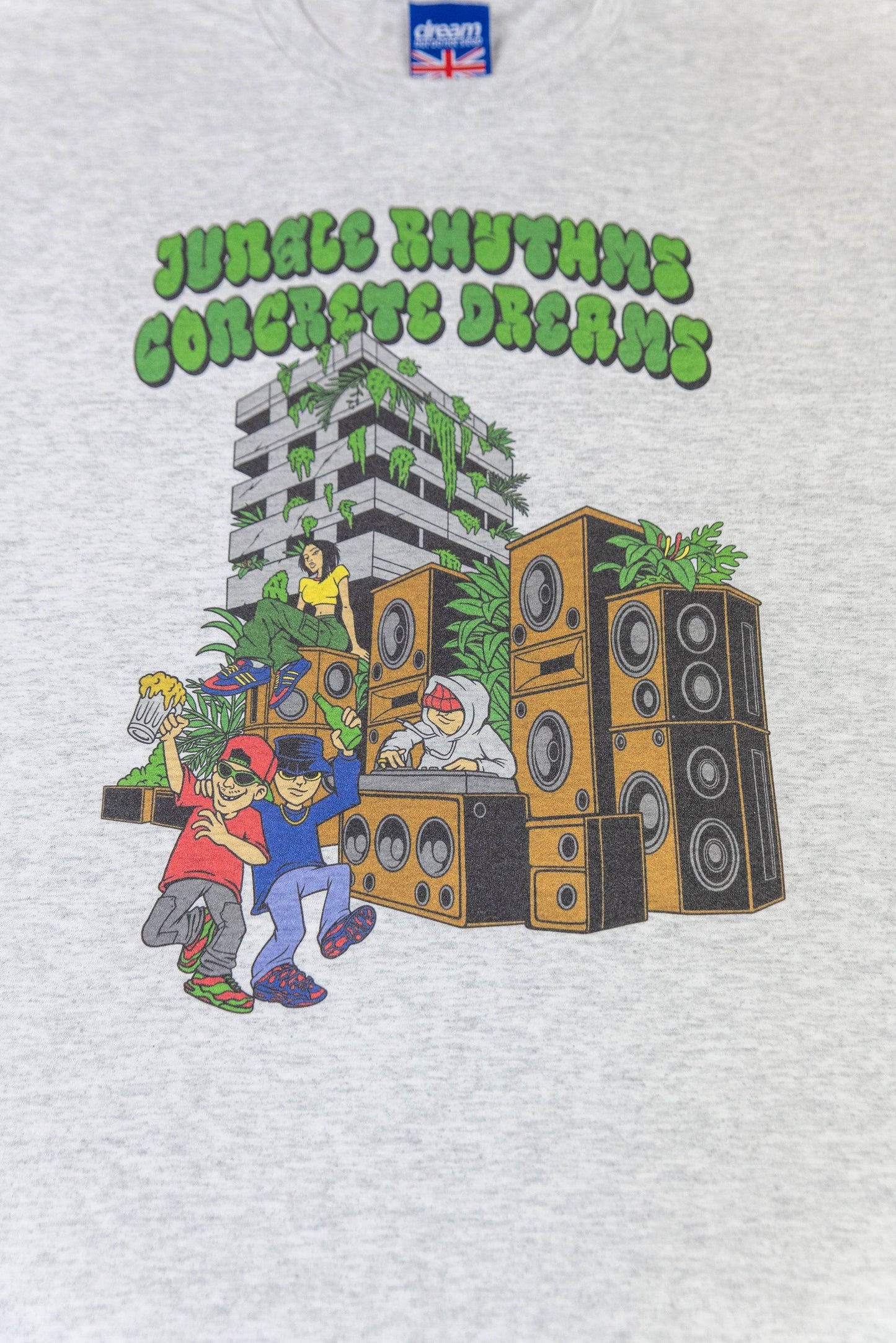 Close-up of Jungle Rhythms Concrete Dreams print on Ash Grey T-Shirt showing vibrant speakers, dancers, and urban jungle scene.