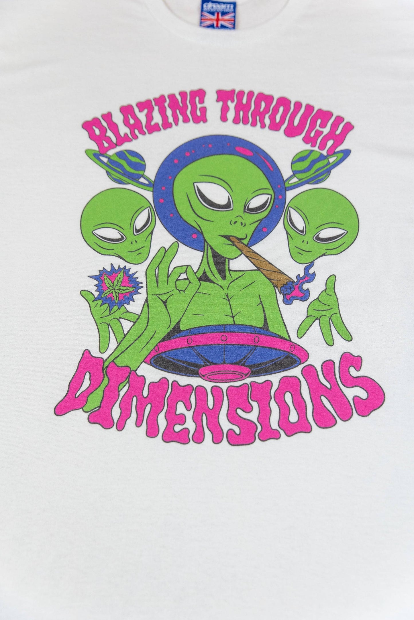 Close-up of alien-themed DTG print on White Graphic T-Shirt - Short Sleeved with bold 'Blazing Through Dimensions' text in pink.