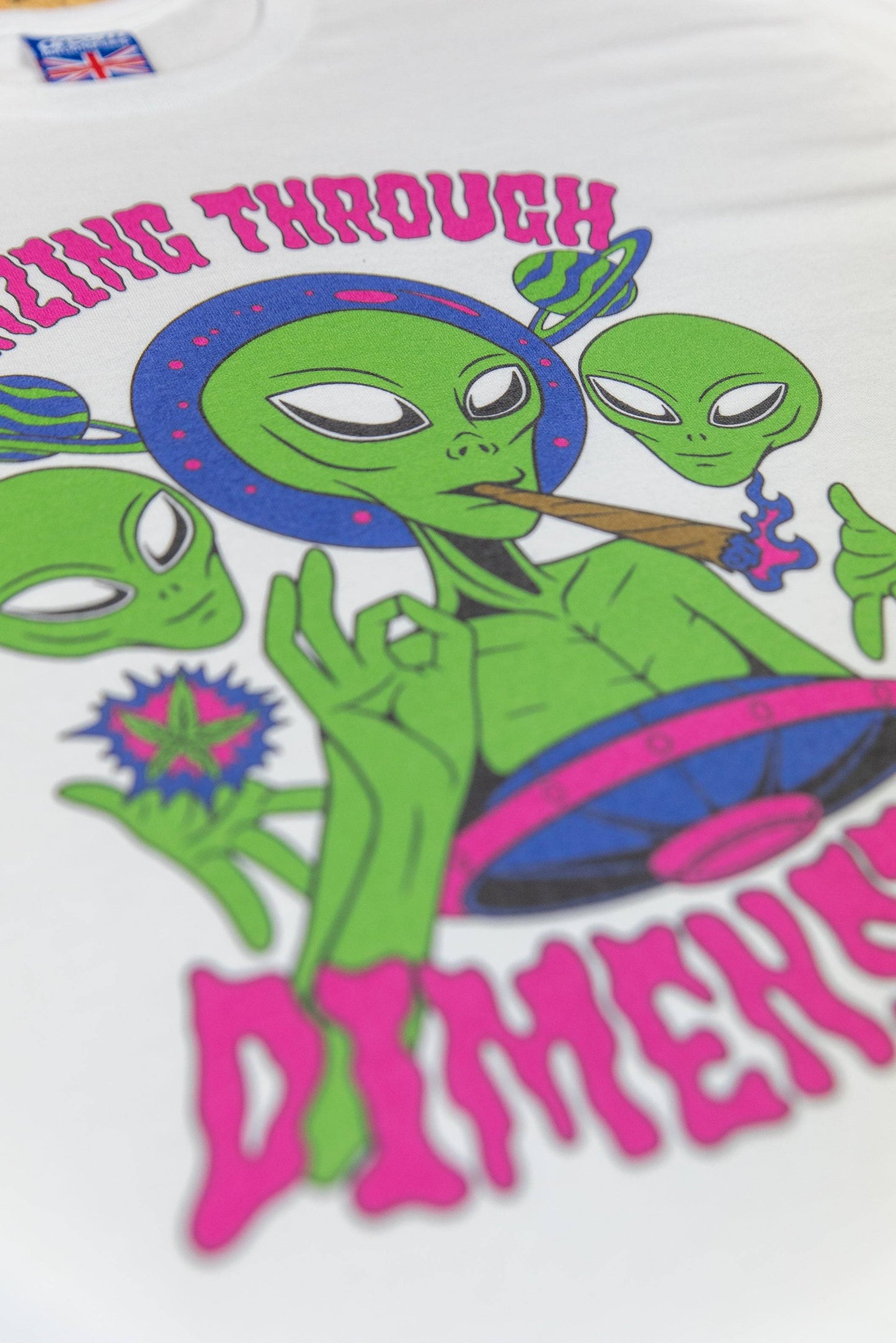 Angled view of White Graphic T-Shirt - Short Sleeved showing vibrant alien trio design and psychedelic colors on soft cotton fabric.