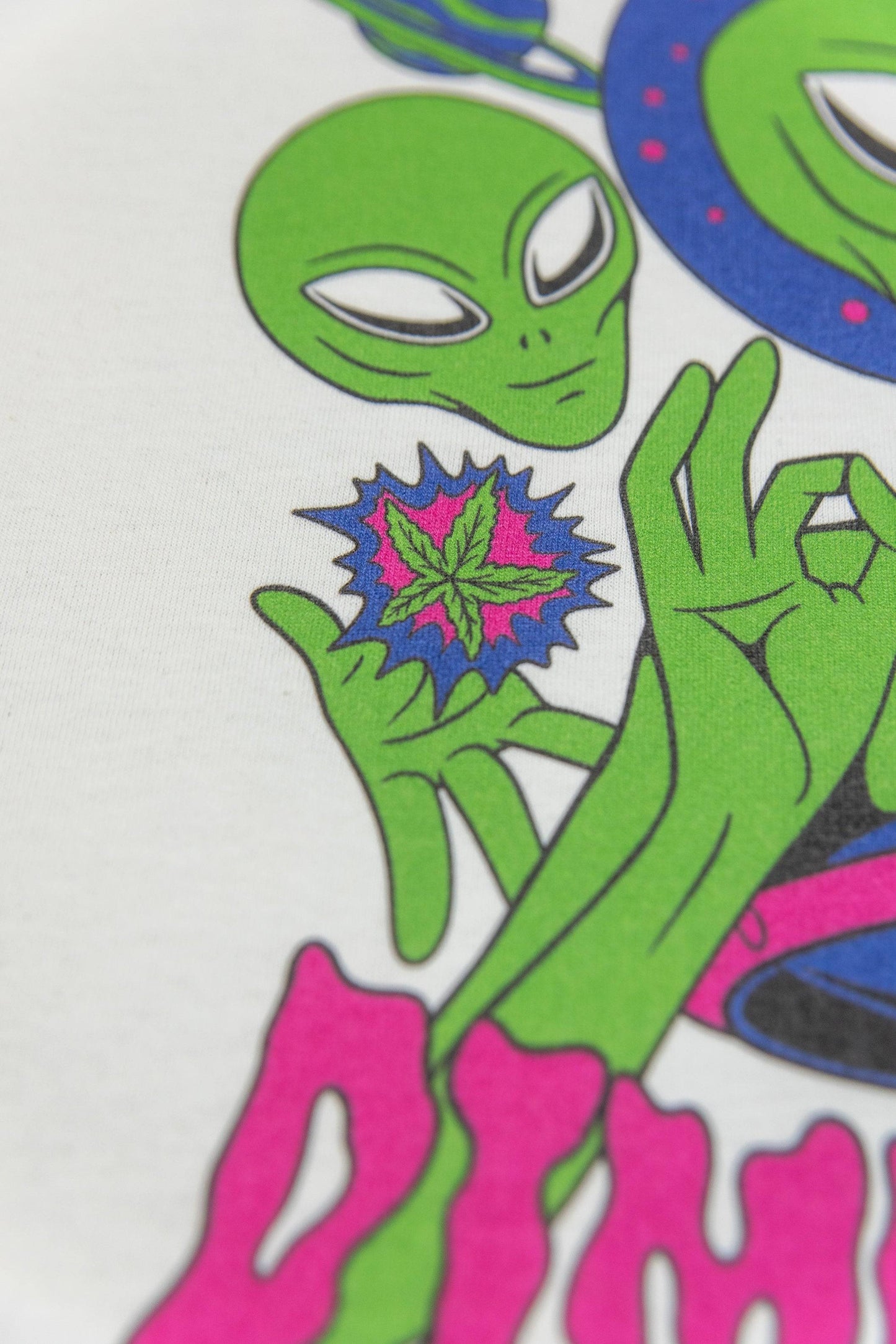 Detailed shot of alien holding a colorful cannabis leaf on White Graphic T-Shirt - Short Sleeved, part of DBDNS Shop's apparel collection.