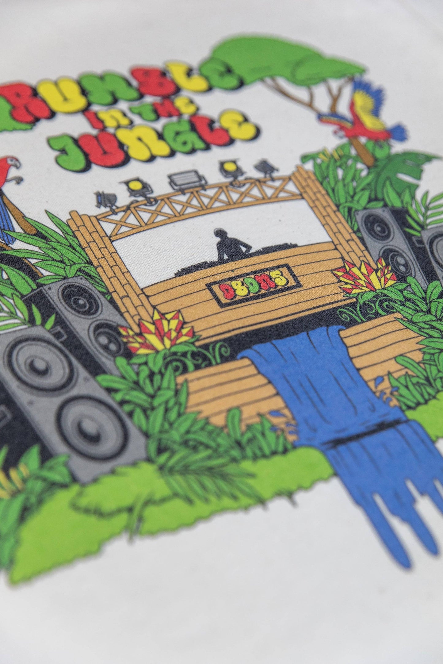 Angled view of Jungle Print Cotton T-Shirt showing detailed DTG illustration with DJ stage, speakers, and waterfall on soft cotton.