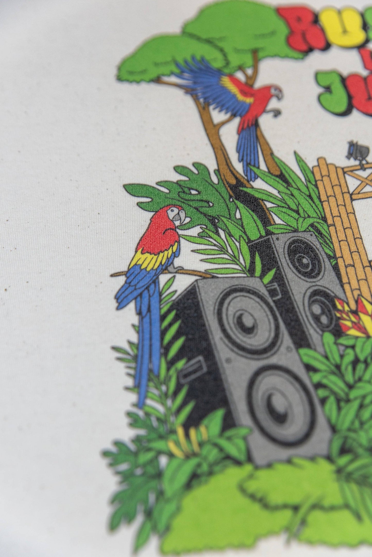 Detailed close-up of parrot and speaker section from Rumble In The Jungle print on relaxed fit cotton t-shirt.