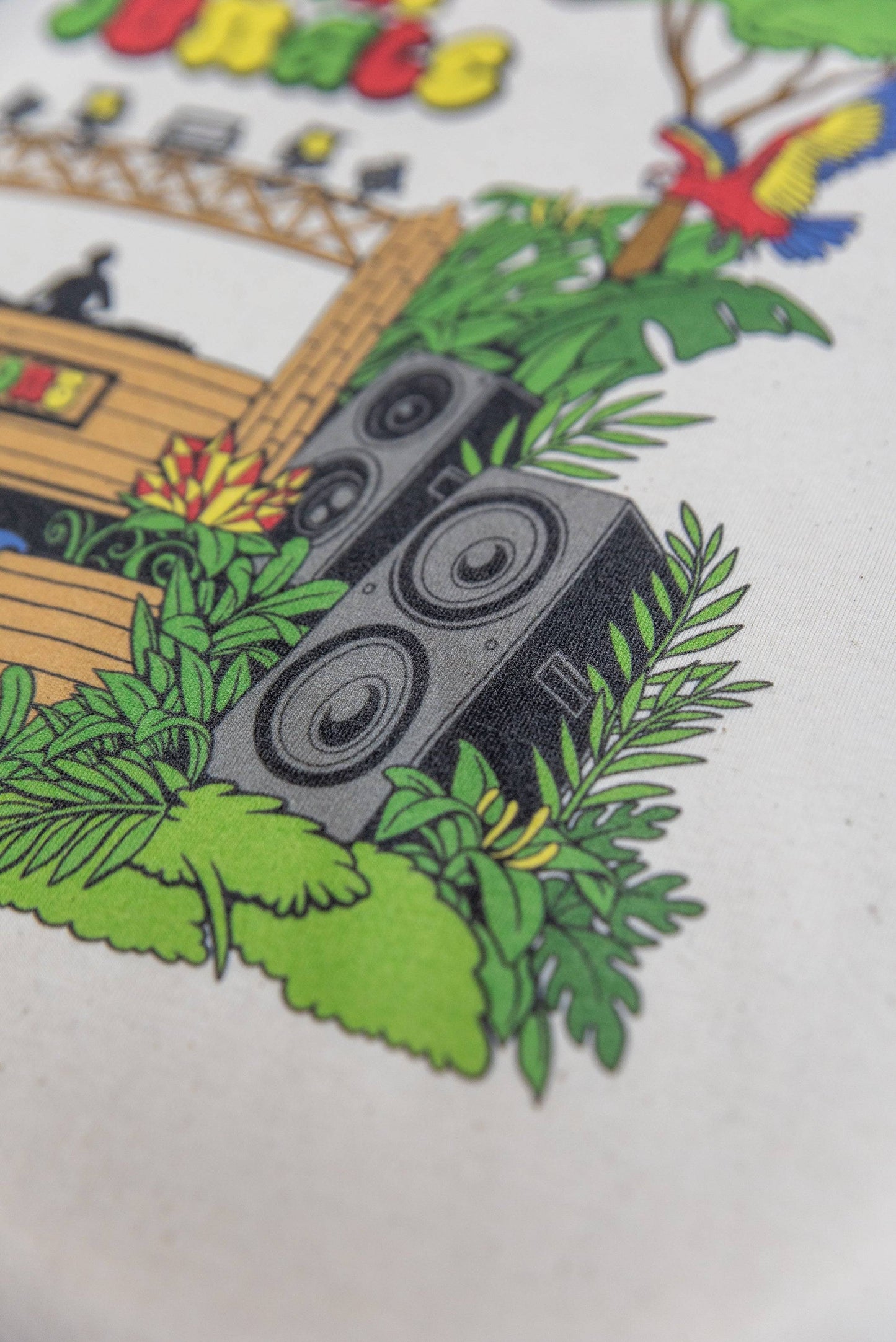 Zoomed-in view of speaker and foliage design on Jungle Print Cotton T-Shirt, highlighting vibrant DTG colors and texture.