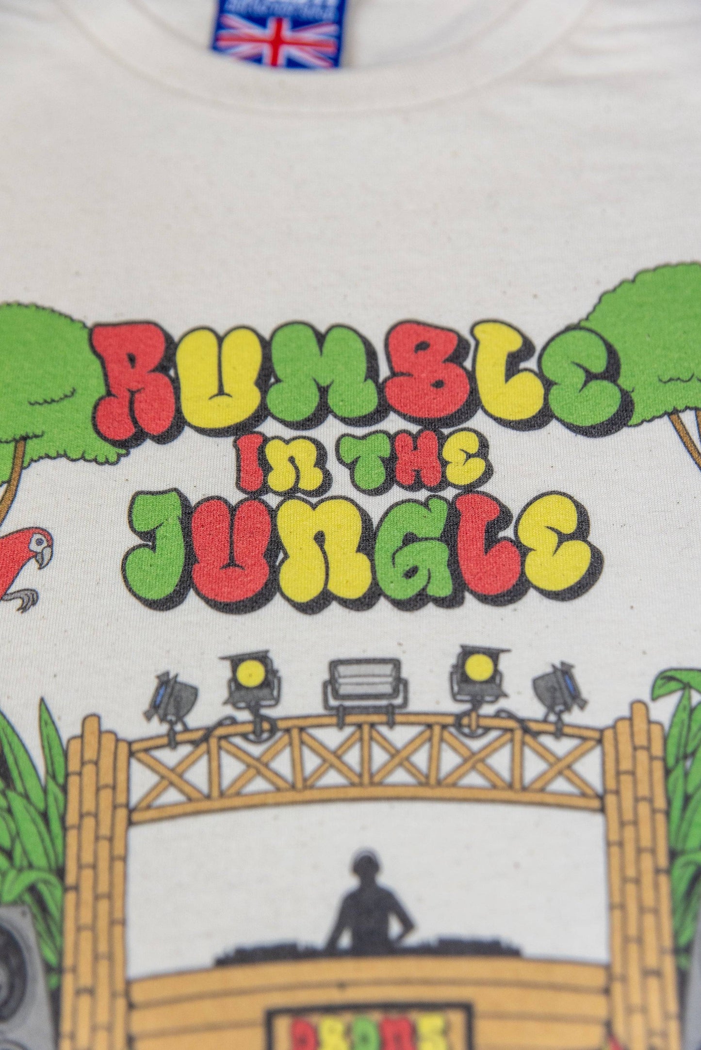 Close-up of colorful 'Rumble In The Jungle' text on natural cotton t-shirt with soft feel and unisex relaxed fit.
