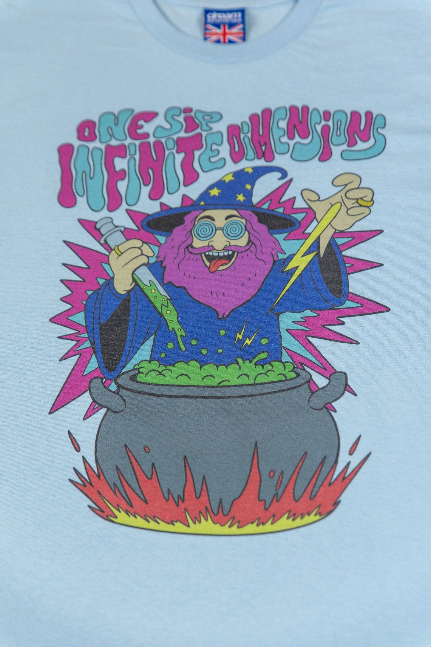 Close-up of Tripping Wizard print on Light Blue T-Shirt Unisex, showing vibrant wizard artwork with 'One Sip Infinite Dimensions' text.