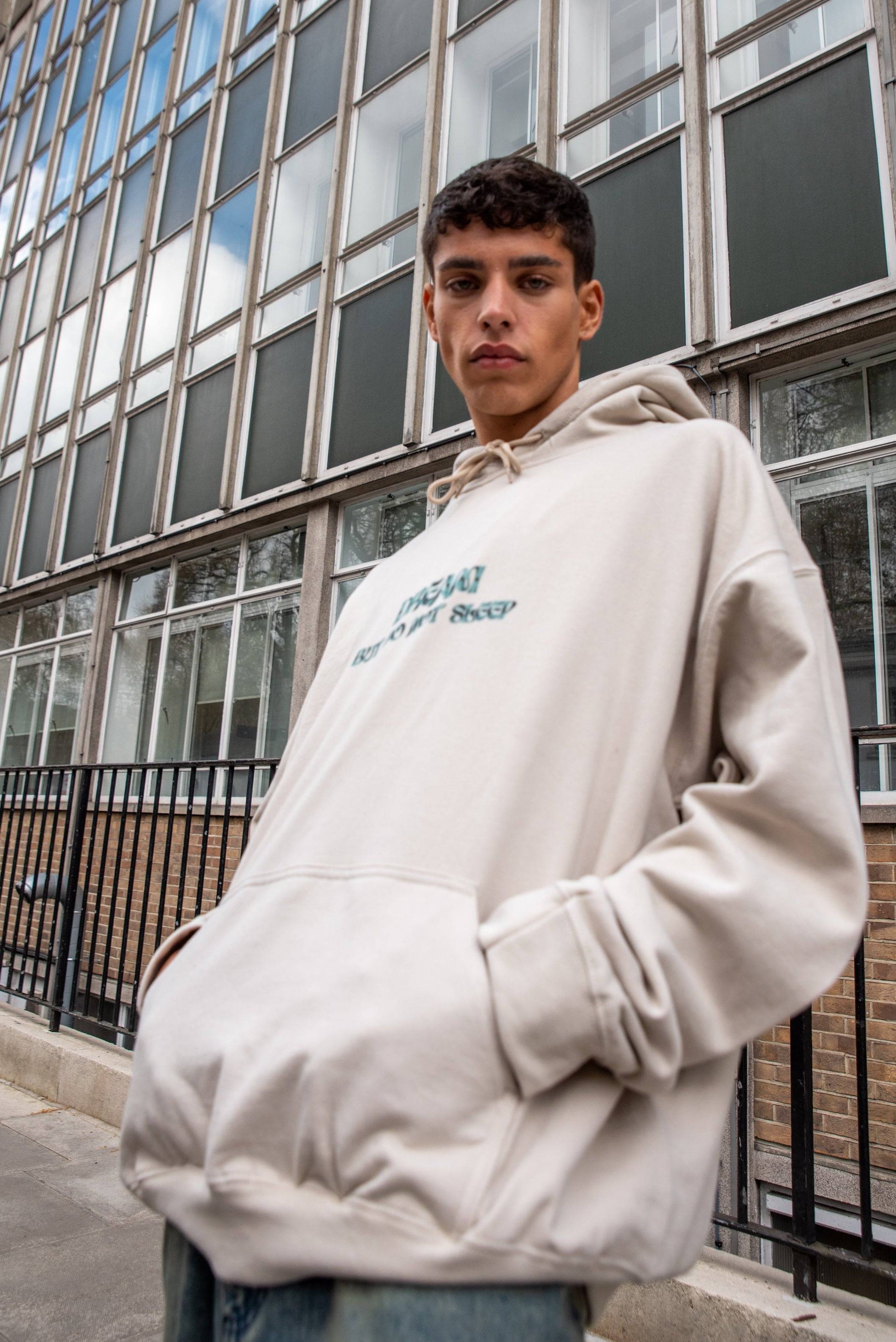 Boxy fit streetwear hoodie in Sand with front logo print, made from heavyweight cotton, styled for a relaxed unisex outerwear look.