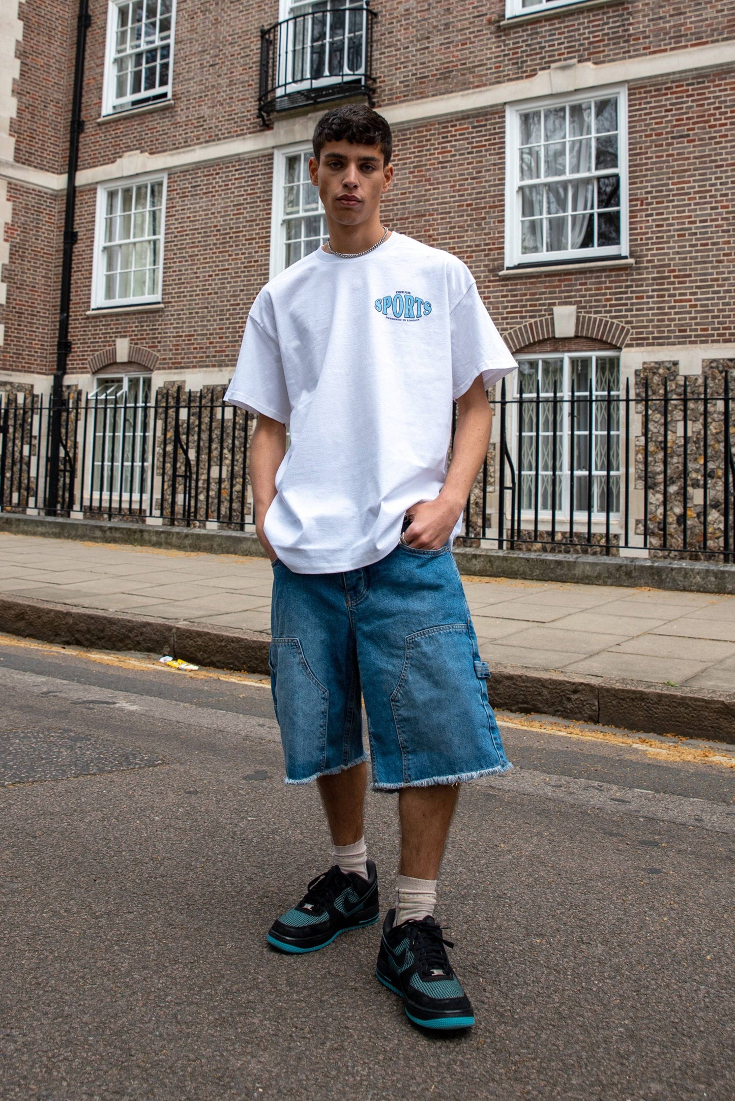 White sport print t-shirt with dream chest design paired with denim shorts and sneakers, showcasing casual streetwear style for men.