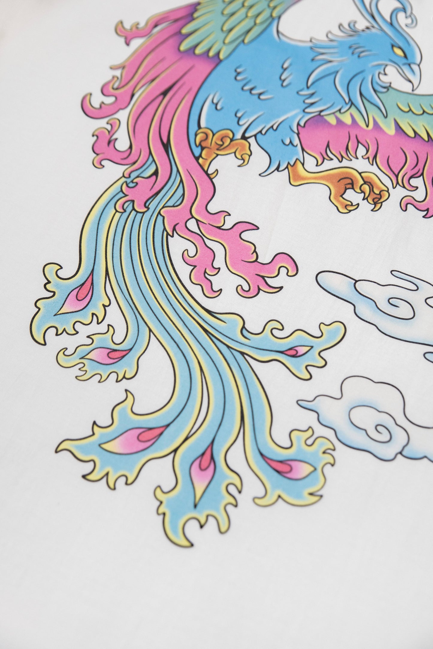 Zoomed-in image of the phoenix tail on the White Phoenix T-Shirt, showcasing intricate color gradients and fine print quality on white cotton.