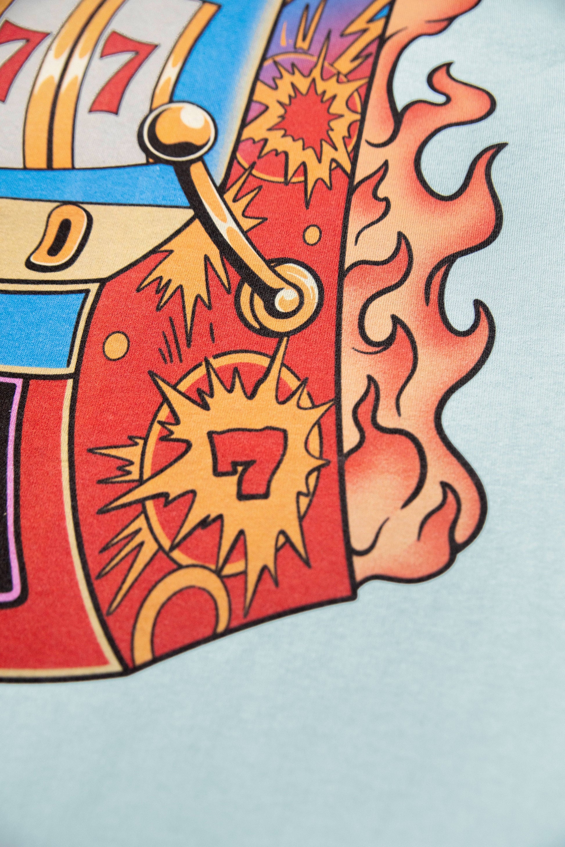 Detailed view of side panel on Lucky No 7 print t-shirt, highlighting comic-style explosion and number 7 artwork.
