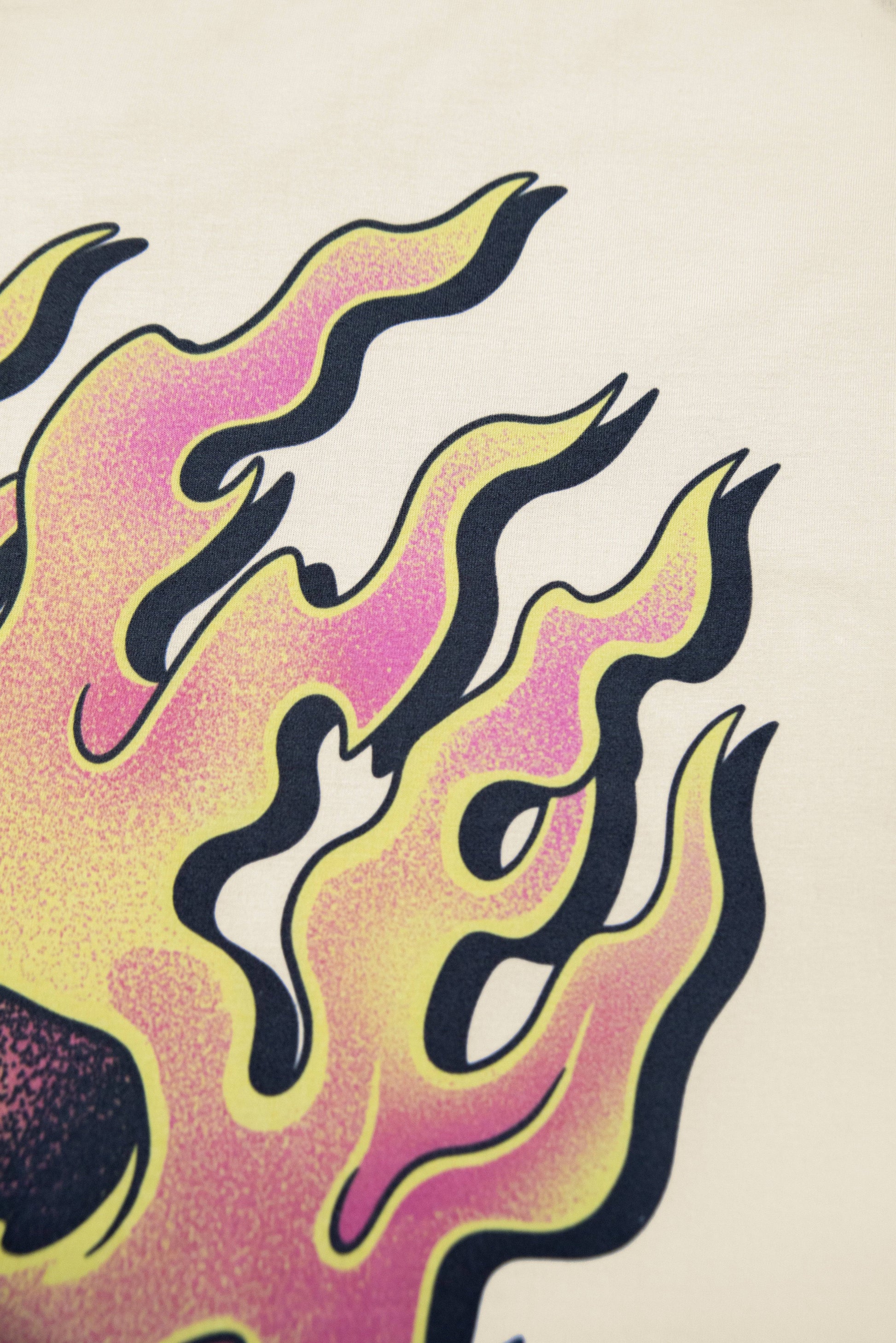 Zoomed-in flames from skull design on sand short sleeved t-shirt, highlighting vibrant colors and bold graphic style.