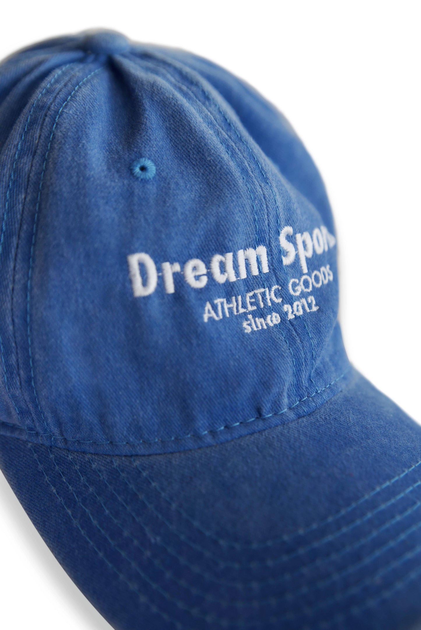 Close-up of Dream Sports logo embroidery on vintage light blue cotton cap, showcasing detailed stitching and durable fabric texture.