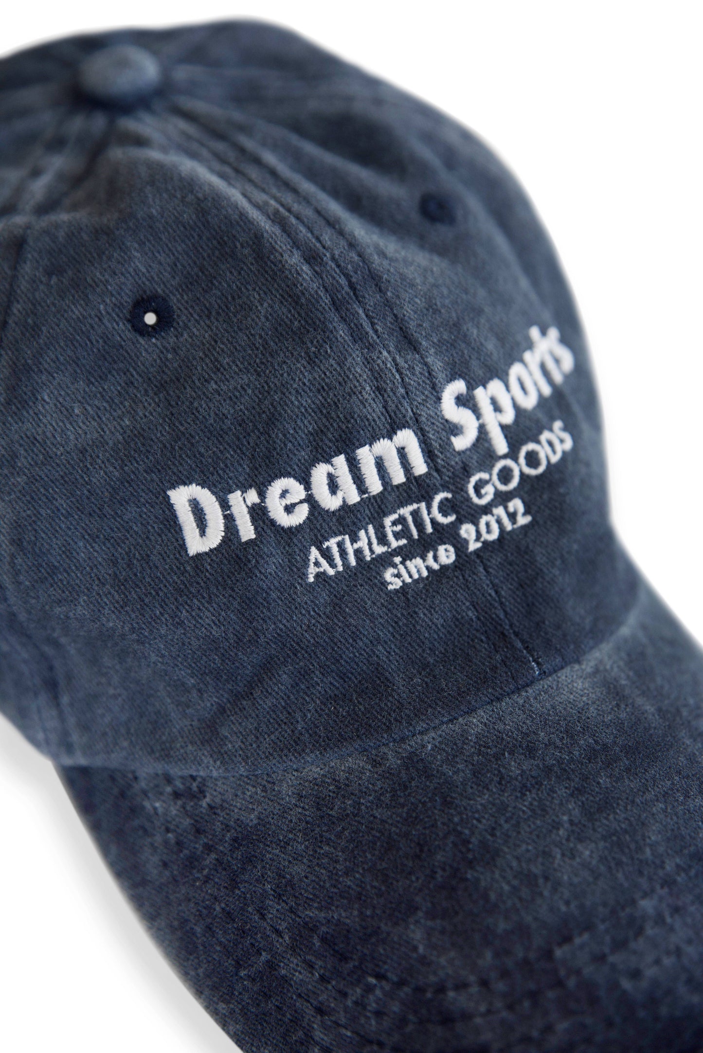 Close-up of Dream Sports logo embroidery on vintage navy cotton baseball cap, showcasing premium stitching and soft washed texture.