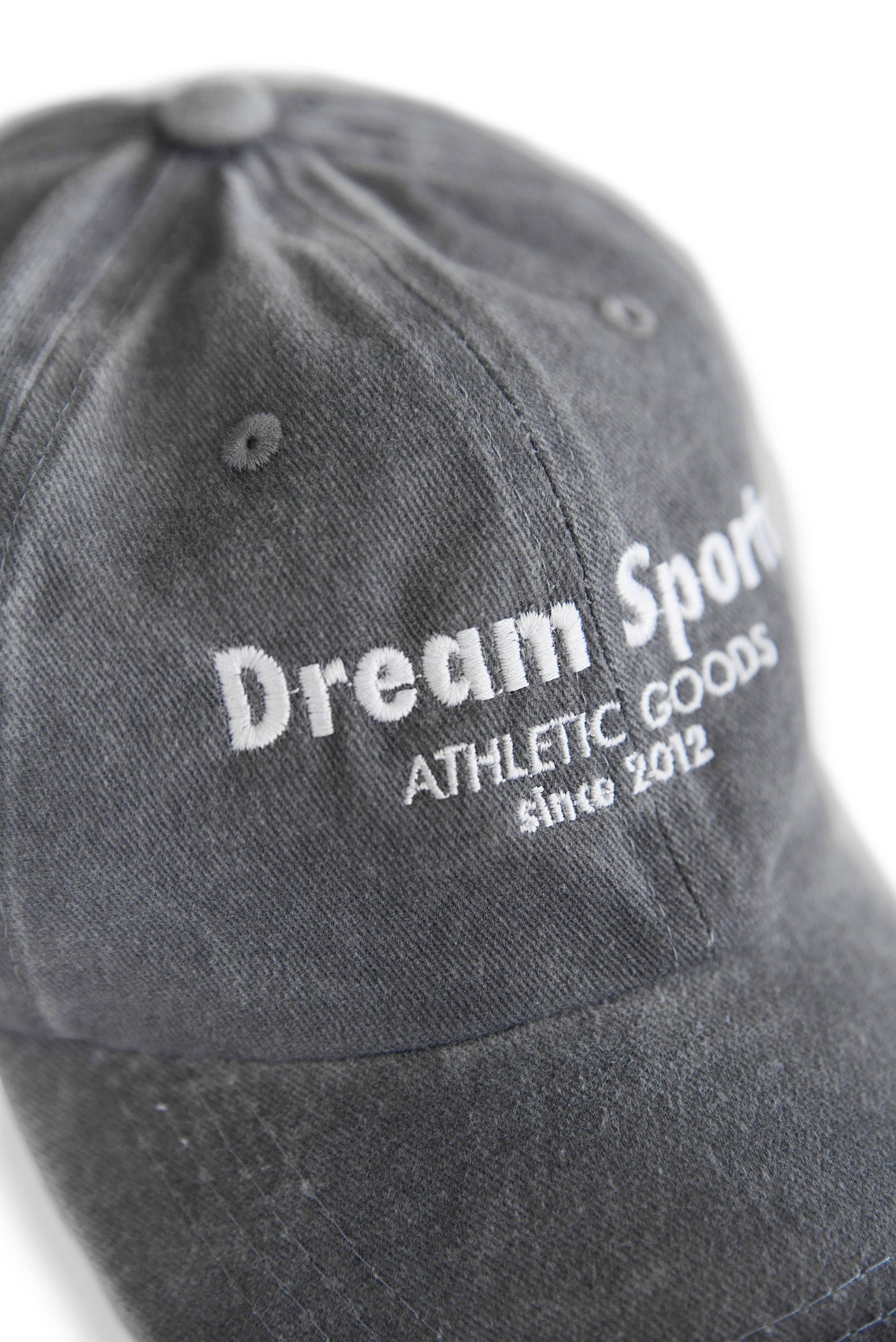 Close-up of Dream Sports logo embroidered on vintage grey cotton baseball cap, showcasing fine stitching and durable fabric.