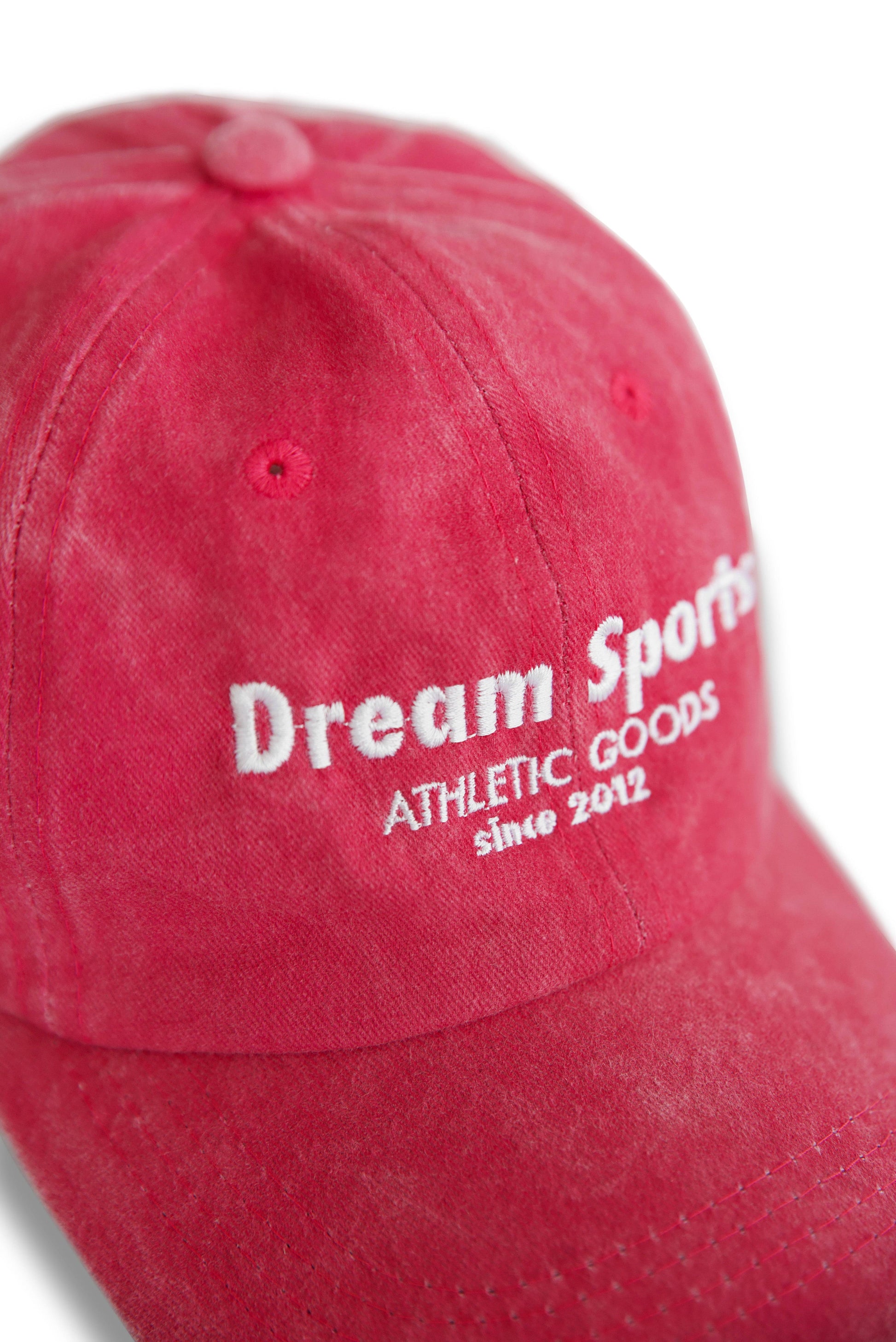 Close-up of Dream Sports logo embroidery on vintage pink cap, showcasing fine stitching and premium fabric texture.