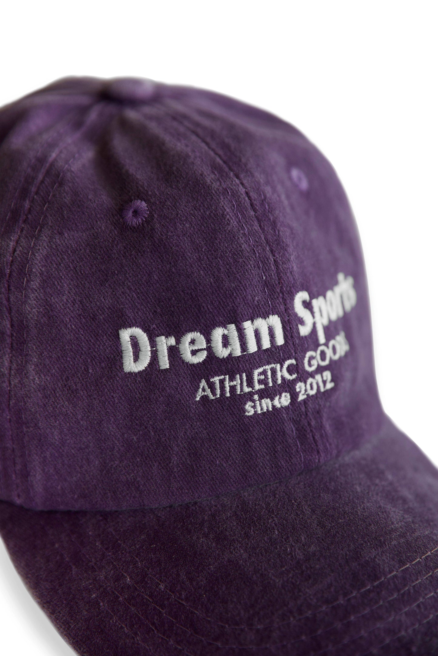 Close-up of Dream Sports logo embroidered on vintage purple cap. High-quality stitching on durable cotton for stylish everyday wear.