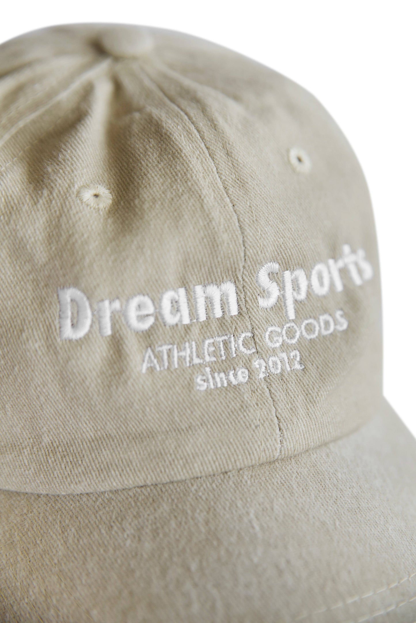 Close-up of Dream Sports logo embroidery on vintage beige cap. High-quality stitching highlights premium design and branding.
