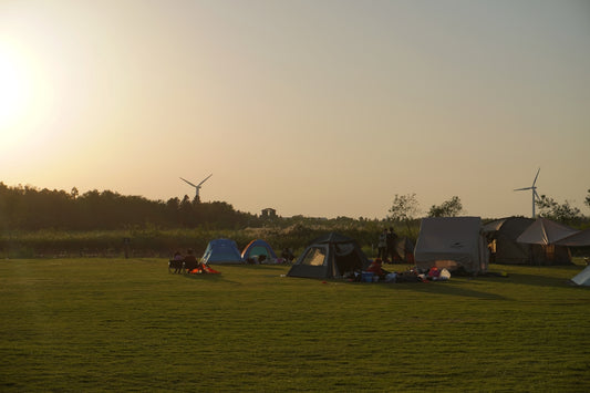 a group of people camping in a field with windmills in the background